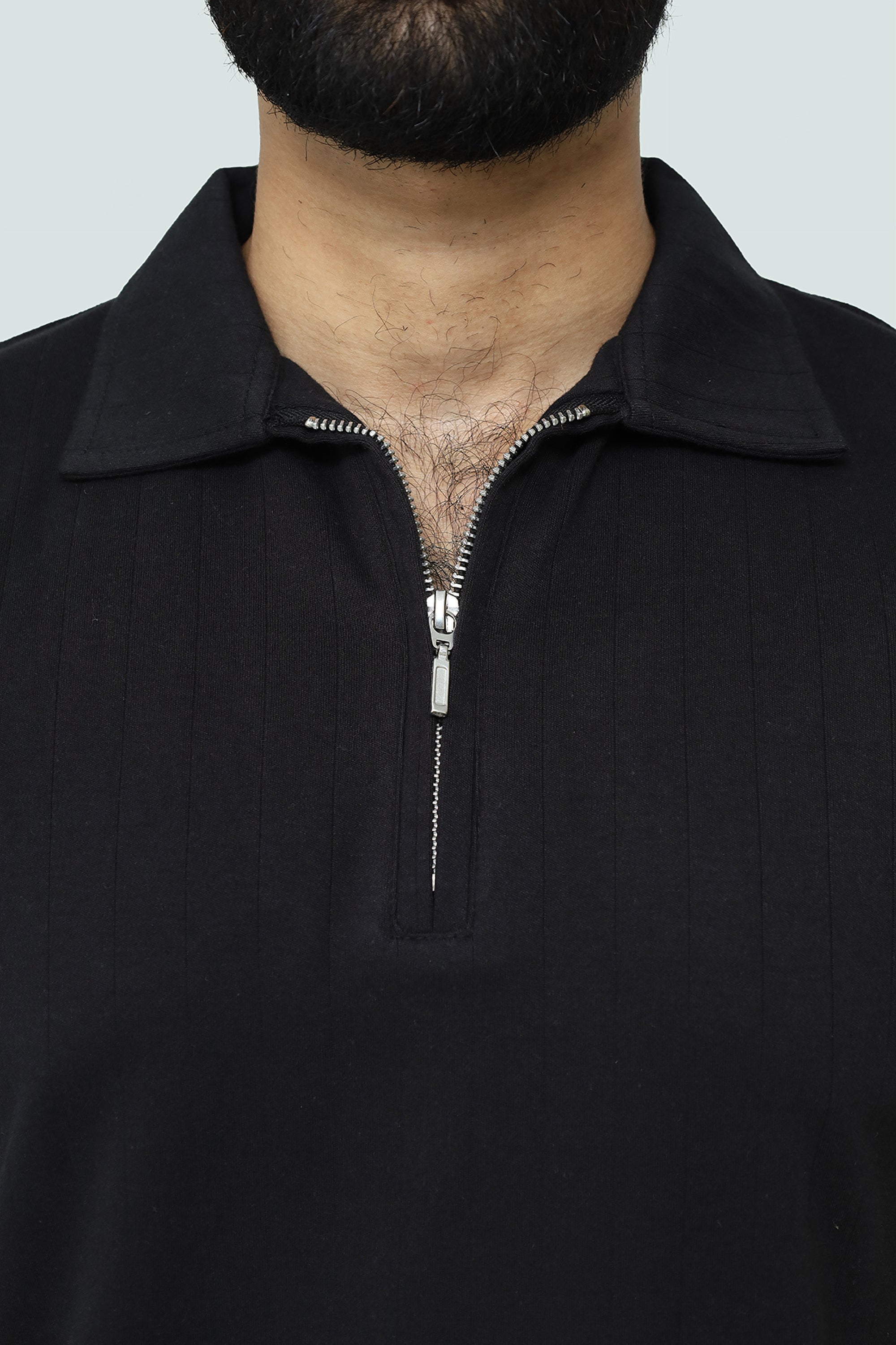 Close-up of a black V neck zip-up polo with a neutral background
