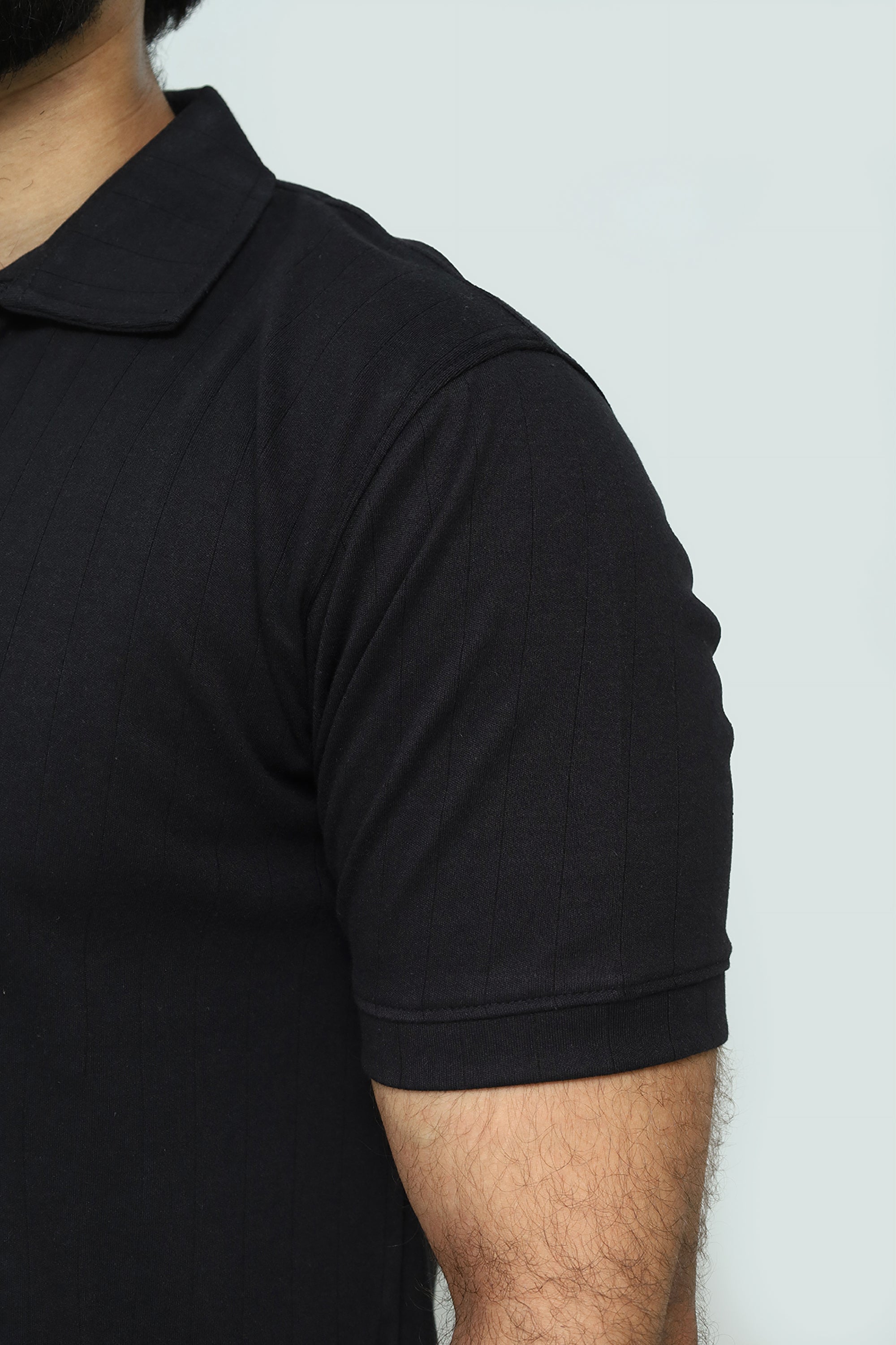 Black polo shirt worn by a person on a white background
