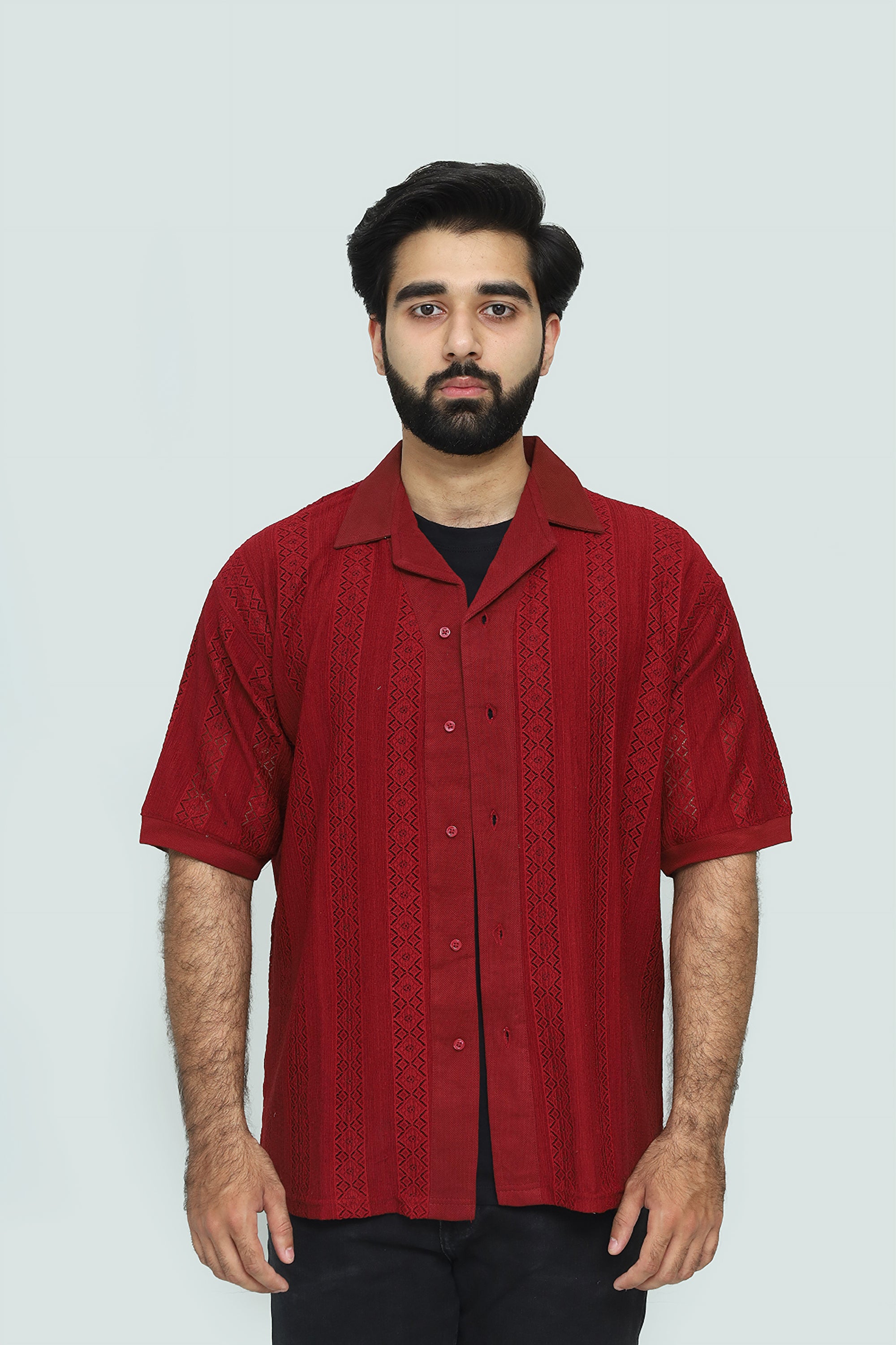 Man wearing a red patterned shirt against a plain background