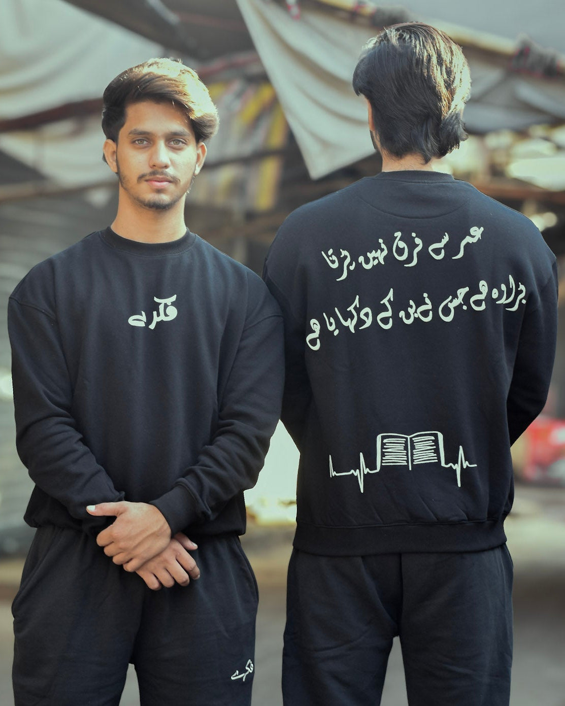 Two people wearing matching black outfits with text and graphics, standing side by side.