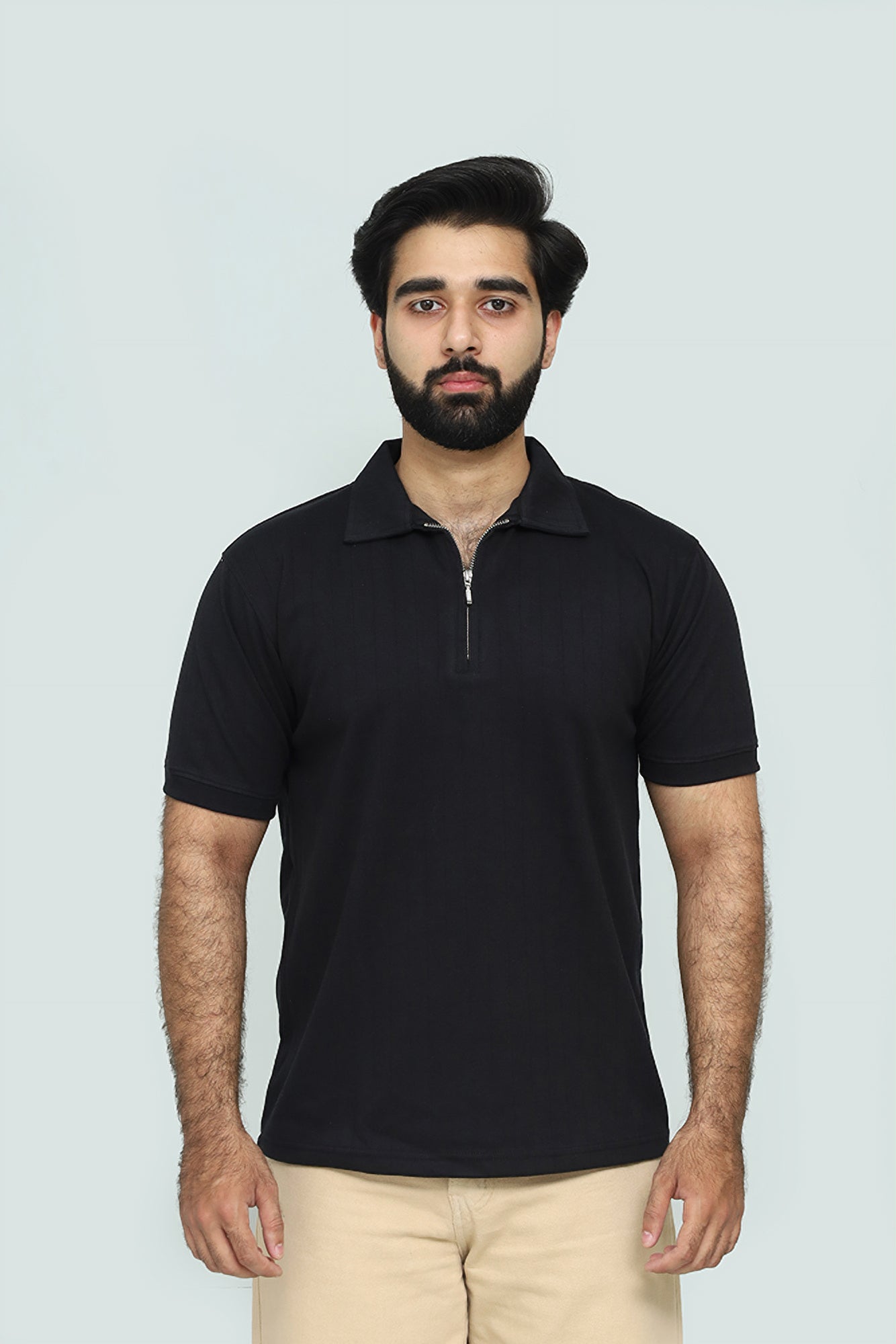 Man wearing a black polo shirt against a light background